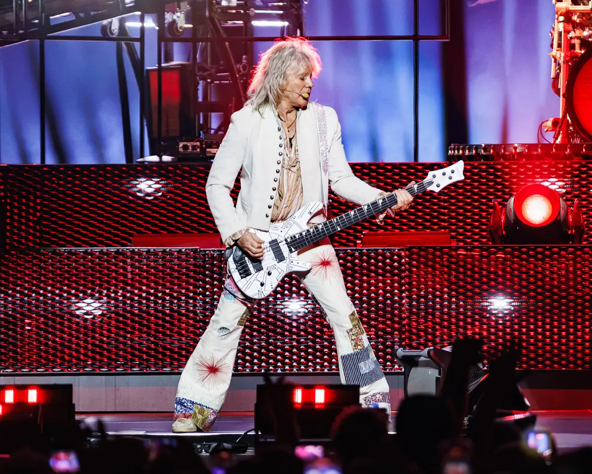 Def Leppard - The O2 Arena London - 2 July 2026 Photo Manuela Langotsch | MetalTalk - Heavy Metal News Reviews and Interviews Rock guitarist in a white embellished suit playing a white electric guitar on a red-lit stage with lattice backdrop.