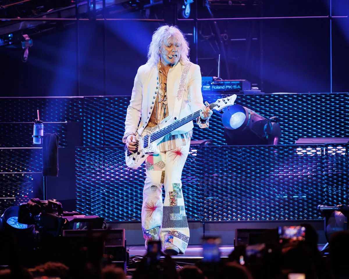 Def Leppard - The O2 Arena London - 2 July 2026 Photo Manuela Langotsch | MetalTalk - Heavy Metal News Reviews and Interviews Guitarist in a white patchwork suit plays a white electric guitar on a blue-lit concert stage.
