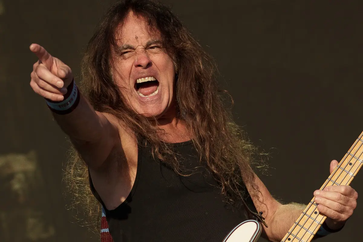 Iron Maiden - Live Is Live Festival Antwerp - 29 June 2026 Photo Dennis De LoorMetalTalk | MetalTalk - Heavy Metal News Reviews and Interviews Rock guitarist with long hair shouting and pointing at the crowd while playing a bass guitar on stage.